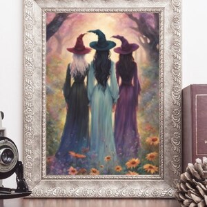 May include: A framed art print depicting three figures wearing pointed hats and long dresses standing in a forest clearing filled with flowers. The figures are shown from behind, with one in a dark dress, one in light blue, and one in purple.