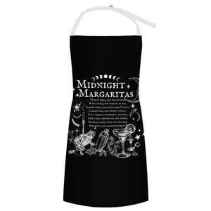 May include: A black apron with white straps featuring the text Midnight Margaritas and a quote from Macbeth. The design includes illustrations of a frog, a cocktail shaker, a margarita glass, stars, moons, and various botanical elements.