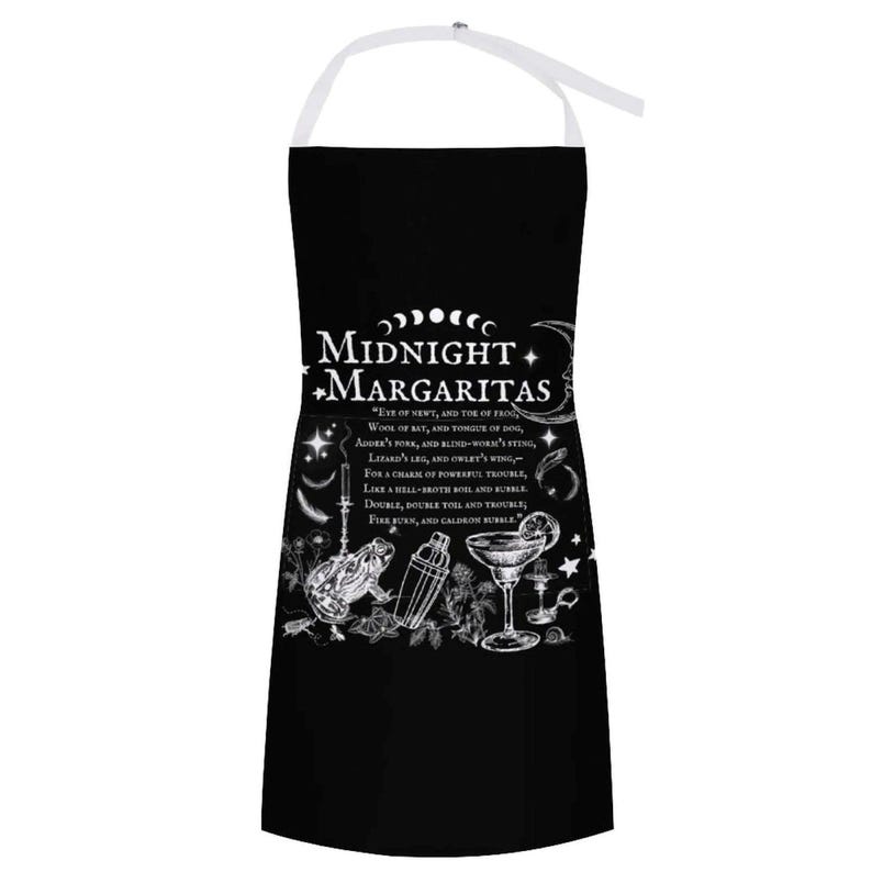 May include: A black apron with white straps featuring the text Midnight Margaritas and a quote from Macbeth. The design includes illustrations of a frog, a cocktail shaker, a margarita glass, stars, moons, and various botanical elements.