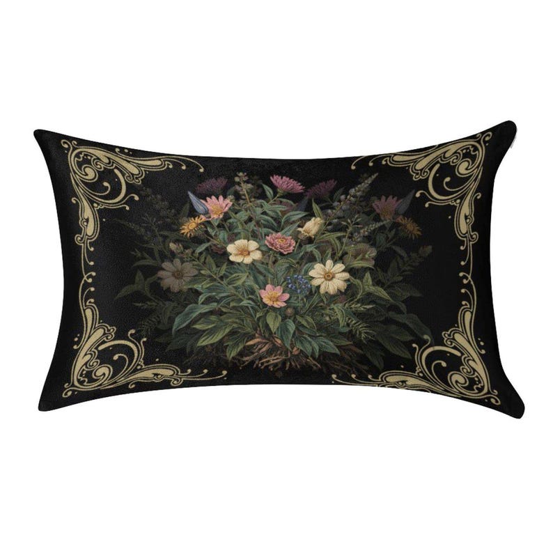 May include: A rectangular throw pillow featuring a black background with a central bouquet of multi-colored flowers including pink, yellow, and white blossoms. The pillow is framed by ornate, light gold scrollwork patterns in each corner.