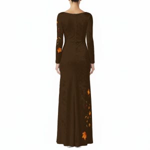 May include: A floor-length, long-sleeved dark brown dress featuring a subtle, textured fabric finish. The garment is adorned with a scattered pattern of vibrant orange and yellow autumn leaves, concentrated along the right sleeve and the lower left side.
