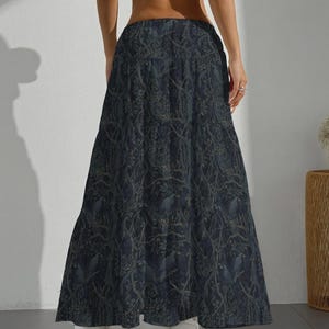 May include: A floor-length, high-waisted maxi skirt in a dark navy blue hue. The fabric features an intricate, repeating pattern of intertwined tree branches and foliage in a muted, lighter blue-grey tone, creating a dense, layered visual effect.