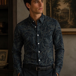 May include: A long-sleeved button-down shirt featuring a dark navy and forest green print of birds perched among tangled tree branches. The shirt has a classic collar, white buttons down the front placket, and is tucked into dark trousers with a black belt.