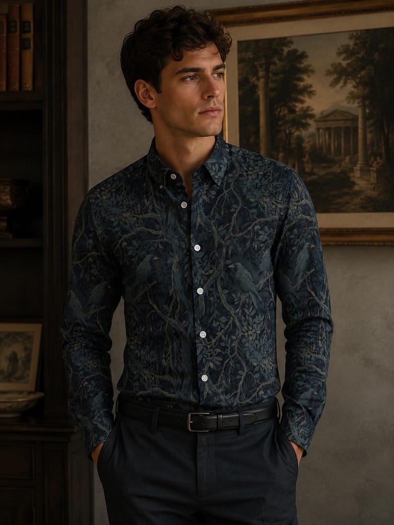 May include: A long-sleeved button-down shirt featuring a dark navy and forest green print of birds perched among tangled tree branches. The shirt has a classic collar, white buttons down the front placket, and is tucked into dark trousers with a black belt.
