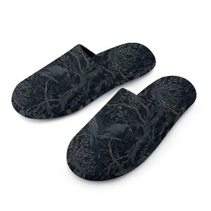 May include: A pair of slip-on house slippers featuring a dark, moody pattern of crows perched on tree branches amidst dense foliage. The design uses shades of black, charcoal, and muted blue, with the birds and trees integrated into the fabric.