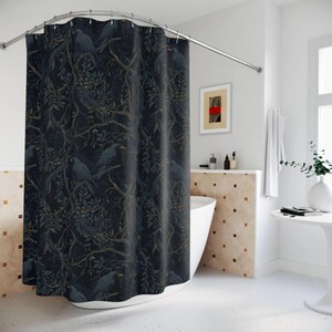 May include: A shower curtain featuring a dark navy blue background with a repeating pattern of black birds perched on intricate, winding tree branches with muted green and gold leaves, suspended from a curved silver metal shower rod.