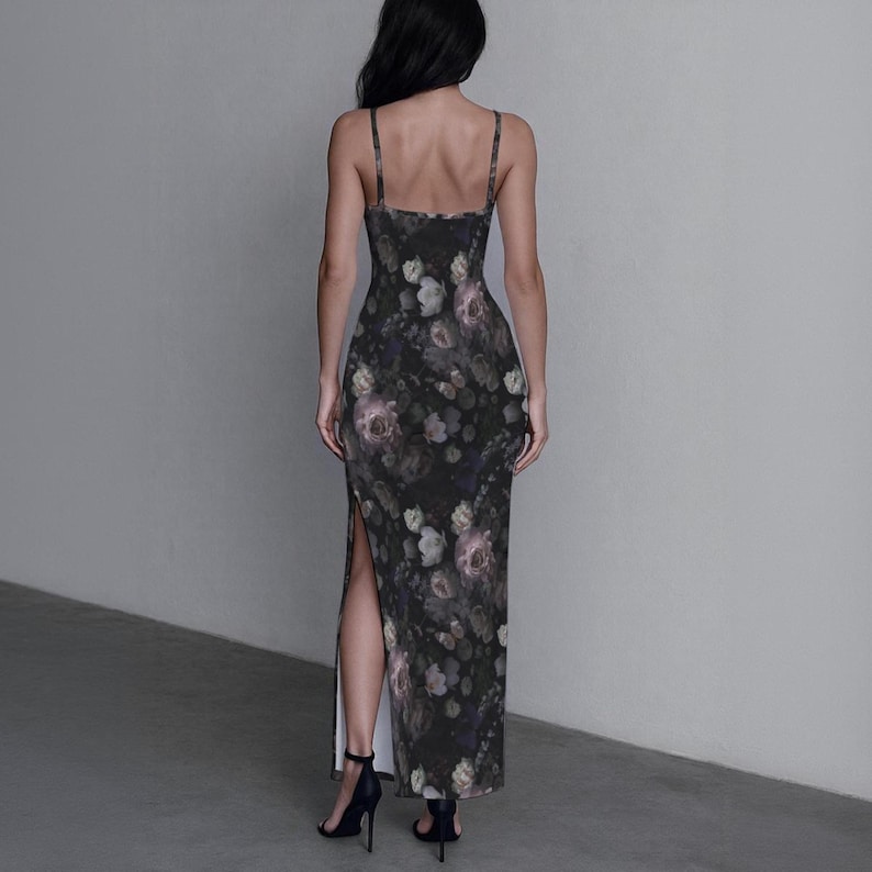 May include: A floor-length, sleeveless dress featuring a dark charcoal background with a muted floral print in shades of dusty pink, cream, and sage green. The garment has thin spaghetti straps, a fitted bodice, and a high side slit on the left leg.