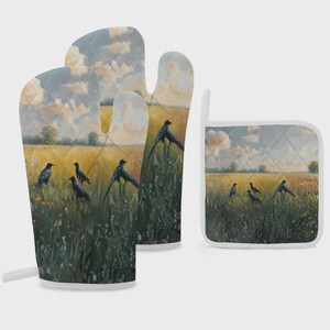 May include: A quilted oven mitt and a square pot holder featuring a printed landscape scene of black crows in a golden wheat field with wildflowers under a cloudy sky. Both items have white trim and a consistent painterly aesthetic design.