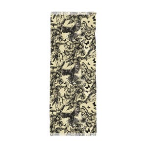 Peut inclure: Un chemin de table rectangulaire au fond cr&egrave;me, orn&eacute; d'un motif r&eacute;p&eacute;titif &agrave; l'encre noire repr&eacute;sentant des oiseaux en vol, des papillons d&eacute;taill&eacute;s et diverses fleurs. Les bords sont termin&eacute;s par une courte frange d&eacute;licate.