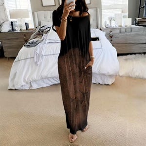 May include: A floor-length maxi dress featuring a black upper section that transitions into a brown, mottled, textured pattern on the lower half. The garment has short sleeves, a wide round neckline, and visible side pockets on the skirt portion.