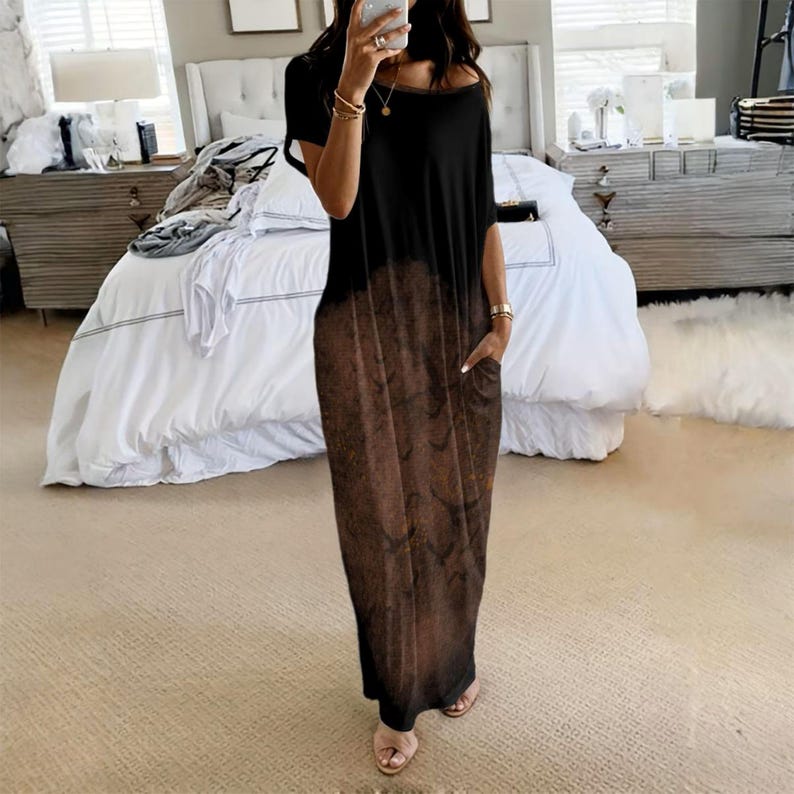 May include: A floor-length maxi dress featuring a black upper section that transitions into a brown, mottled, textured pattern on the lower half. The garment has short sleeves, a wide round neckline, and visible side pockets on the skirt portion.
