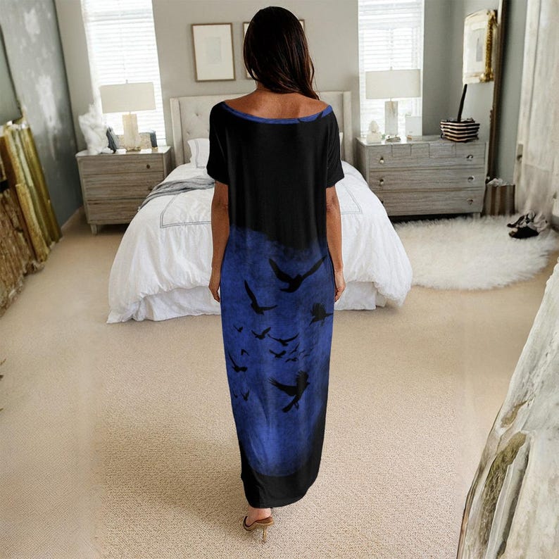 May include: A floor-length short-sleeve dress featuring a black base color with a large, circular blue graphic print on the lower portion. The blue area contains a pattern of multiple black bird silhouettes in various sizes and flight positions.