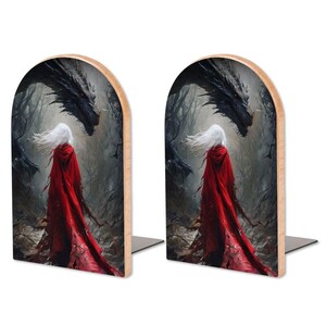 K&ouml;nnte beinhalten: Ein Paar gew&ouml;lbte Buchst&uuml;tzen mit einer gedruckten Illustration einer Figur mit langem wei&szlig;em Haar und einem flie&szlig;enden roten Umhang, die in einem dunklen, nebligen Wald einem gro&szlig;en, dunklen, geschuppten Drachen mit leuchtenden Augen gegen&uuml;bersteht.