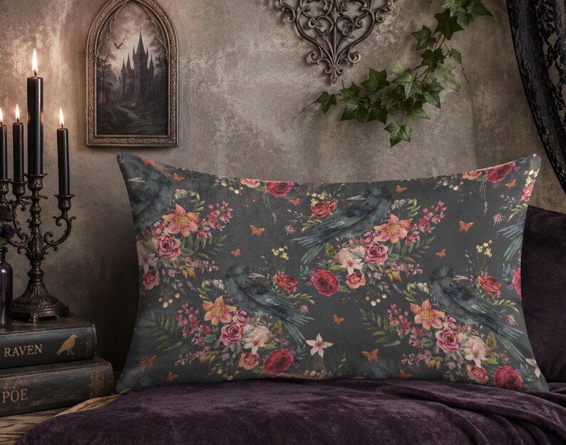 May include: A rectangular throw pillow featuring a dark gray background with a repeating pattern of black ravens, deep red roses, orange lilies, and small green leaves. The design includes tiny orange butterflies scattered among the floral elements.