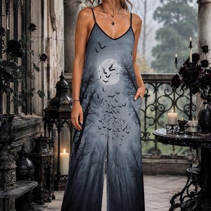 May include: A sleeveless jumpsuit featuring a gray and black gradient print of a full moon, silhouetted trees, and a flock of flying bats. The garment has thin spaghetti straps, a V-neckline, and wide-leg trousers with side pockets.