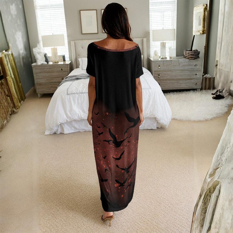 May include: A floor-length short-sleeve dress featuring a solid black upper section that transitions into a dark red lower section adorned with a repeating pattern of black flying birds. The garment has a wide, rounded neckline and a loose fit.