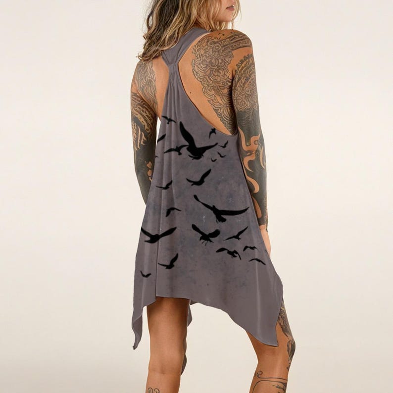 May include: A grey racerback tank top with an asymmetrical hemline, featuring a printed pattern of multiple black birds in flight across the fabric. The garment has a sleeveless design with a gathered neckline and a loose, flowing silhouette.