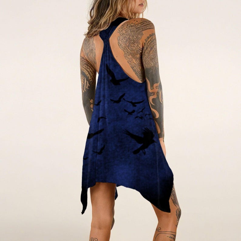 May include: A dark blue racerback tank top featuring a printed pattern of black birds in flight. The garment has an asymmetrical hemline with pointed sides and a sleeveless design, showcasing a deep navy hue with a subtle mottled texture throughout.
