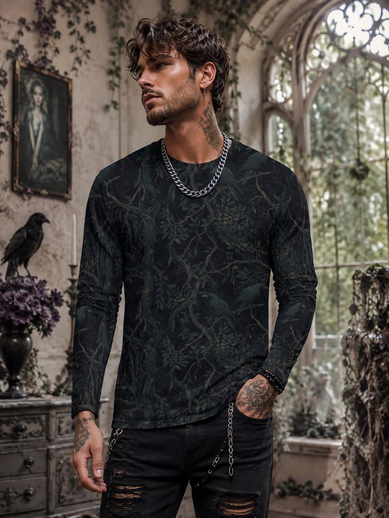 Pode incluir: Uma camisola de manga comprida com gola redonda com um estampado de floresta escura com ramos entrela&ccedil;ados, folhas e silhuetas subtis de p&aacute;ssaros em tons de verde escuro, carv&atilde;o e preto, combinada com cal&ccedil;as de ganga pretas rasgadas e uma corrente prateada.
