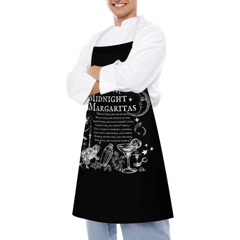 May include: A black apron featuring a white graphic print with the text "MIDNIGHT MARGARITAS" and a poem excerpt. The design includes illustrations of a crescent moon, a frog, a cocktail shaker, a margarita glass, and stars in a white ink style.