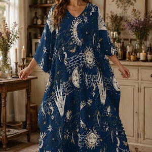 Könnte beinhalten: Ein marineblaues Kaftankleid mit einem weißen und goldenen Himmelsdruck aus Sonnen, Monden, Sternen und Handmotiven, akzentuiert durch kursive Schriftzüge. Das Kleid hat einen V-Ausschnitt, weite Dreiviertelärmel und eine locker fallende Silhouette.