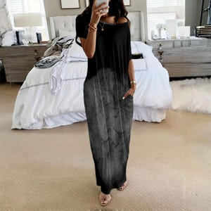 May include: A floor-length black dress with short sleeves and a round neckline. The garment features a gradient effect that transitions from solid black at the top to a faded, mottled grey pattern at the bottom, including side pockets.