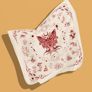 May include: A square off-white bandana featuring a central dark red moth illustration with root-like appendages. The fabric is decorated with a repeating pattern of mushrooms, celestial moon phases, stars, and botanical sprigs, framed by ornate corner flourishes.