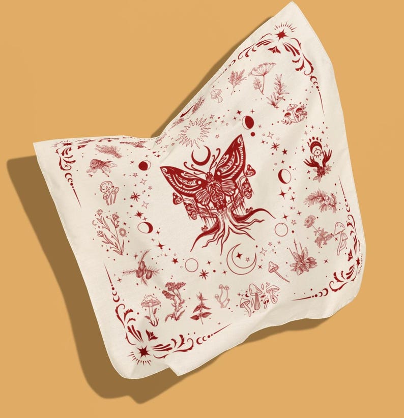 May include: A square off-white bandana featuring a central dark red moth illustration with root-like appendages. The fabric is decorated with a repeating pattern of mushrooms, celestial moon phases, stars, and botanical sprigs, framed by ornate corner flourishes.
