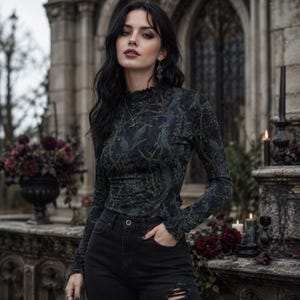 May include: A long-sleeved, high-neck top featuring a dark, intricate forest-inspired print with muted green and gold tones. The garment is paired with black denim jeans that have distressed detailing at the knees and a classic button-fly closure.