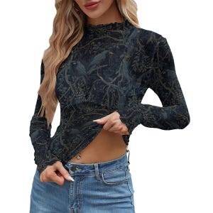 May include: A long-sleeve mock neck top featuring a dark forest print with silhouettes of birds perched on tree branches. The fabric has a subtle texture and a fitted silhouette, paired with blue denim jeans that have a visible metal button closure.