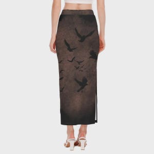May include: A long, dark brown skirt featuring a flock of black birds in flight. The skirt has a high waist and a slit on the side. The birds are silhouetted against a textured background.