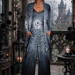May include: A sleeveless jumpsuit and matching long-sleeve open cardigan set featuring a dark gray and black gradient print of a forest, a full moon, and a flock of flying bats. The jumpsuit has a V-neckline and side pockets with wide-leg trousers.