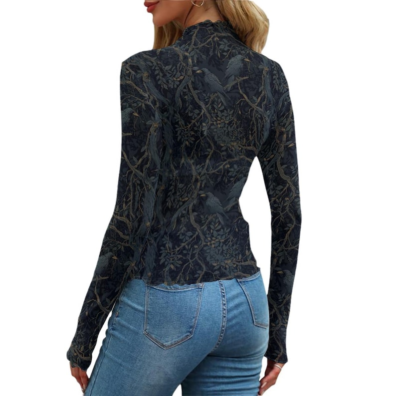 May include: A long-sleeved mock neck top featuring a dark navy and black pattern of birds perched on intricate tree branches with leaves. The fitted garment is paired with light blue denim jeans that have a classic five-pocket design and stitching.