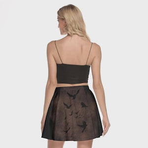 May include: A black crop top and a flared skirt with a brown and black bird design. The skirt features a flock of birds in flight, creating a unique and artistic pattern. The outfit is suitable for casual wear.