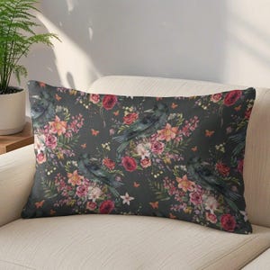 May include: A rectangular throw pillow featuring a dark charcoal gray background with a repeating pattern of black crows, vibrant red roses, pink lilies, green foliage, and small orange butterflies scattered throughout the floral arrangement.
