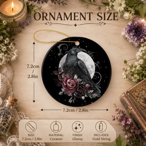 May include: A round ceramic ornament featuring a black raven perched before a full moon, surrounded by dark red roses and stars. The ornament measures 2.8 inches in diameter and includes a gold string. Text on the image reads ORNAMENT SIZE.