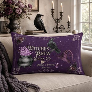 May include: A rectangular purple throw pillow featuring a black cauldron filled with light purple bubbles, a black raven, and a purple witch hat. The text reads Witches Brew Drink Co. Brews & Potions Since 1692, surrounded by ornate decorative borders.