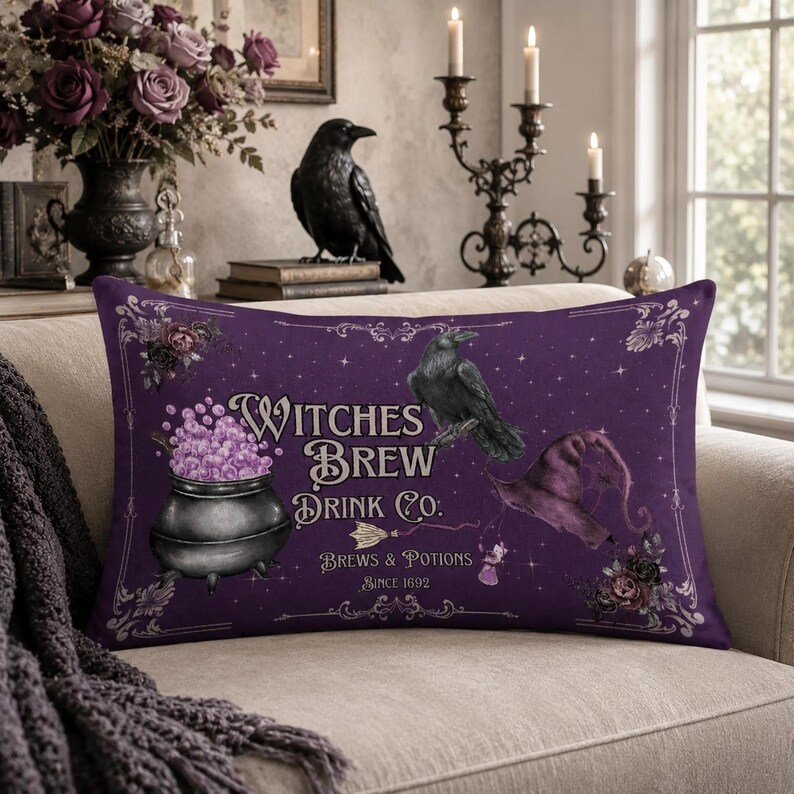 May include: A rectangular purple throw pillow featuring a black cauldron filled with light purple bubbles, a black raven, and a purple witch hat. The text reads Witches Brew Drink Co. Brews & Potions Since 1692, surrounded by ornate decorative borders.