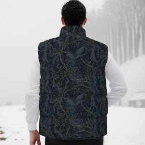 May include: A sleeveless puffer vest featuring a dark navy blue background with a repeating pattern of black crows perched on intricate, winding tree branches with muted green leaves. The vest has a high collar and a quilted, padded construction.