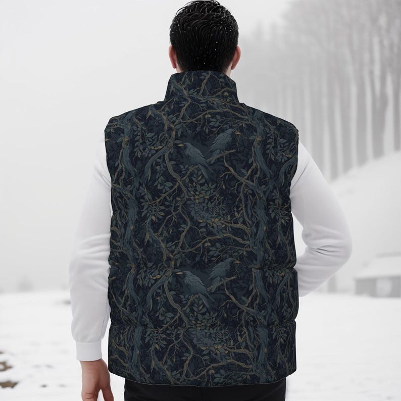May include: A sleeveless puffer vest featuring a dark navy blue background with a repeating pattern of black crows perched on intricate, winding tree branches with muted green leaves. The vest has a high collar and a quilted, padded construction.