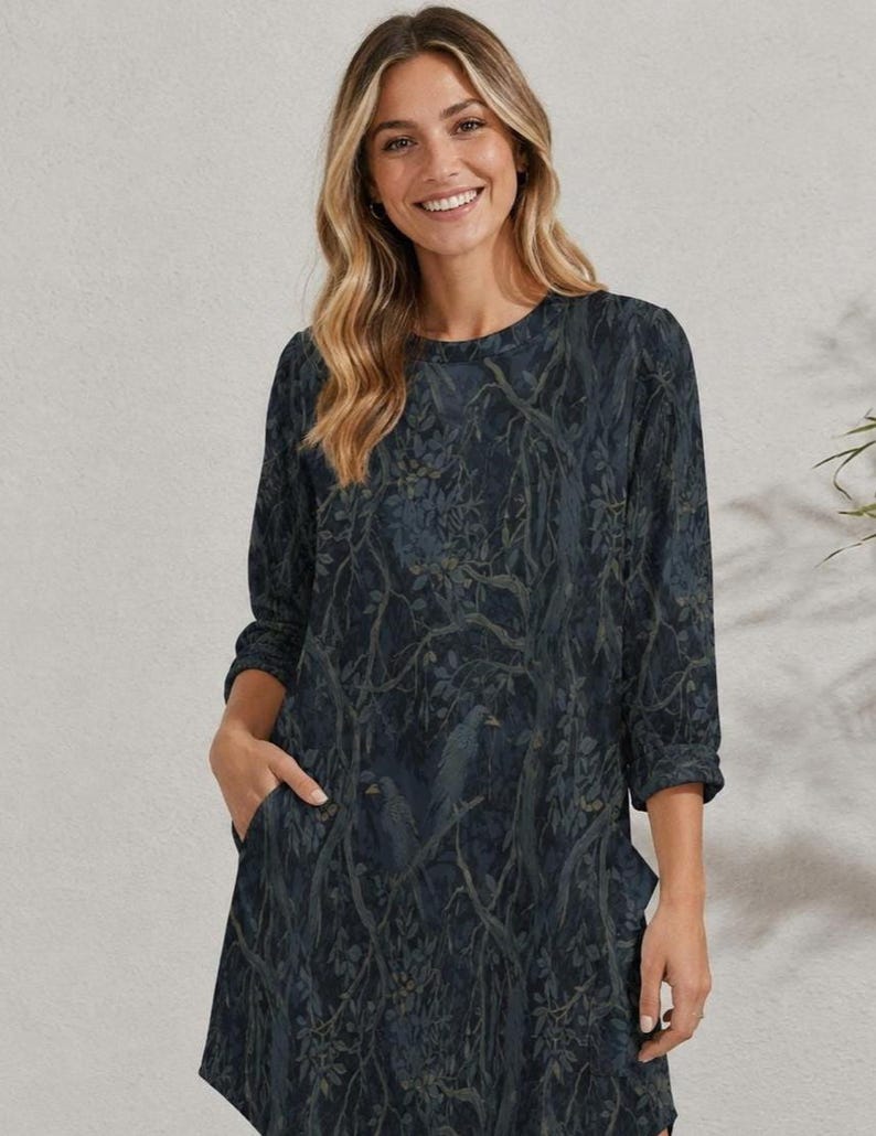 May include: A dark navy blue dress featuring a long-sleeve design with a round neckline and a repeating pattern of forest branches and leaves in muted tones. The garment includes functional side pockets and a straight hemline reaching mid-thigh.