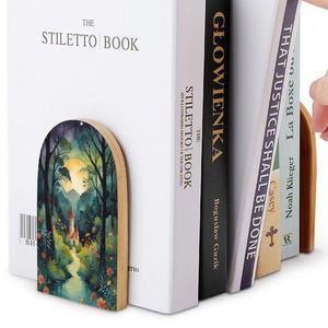 May include: Wooden bookends with a painted forest scene, holding several books. The bookends feature a curved top and a natural wood edge. The books include "THE STILETTO BOOK" and "THAT JUSTICE SHALL BE DONE".