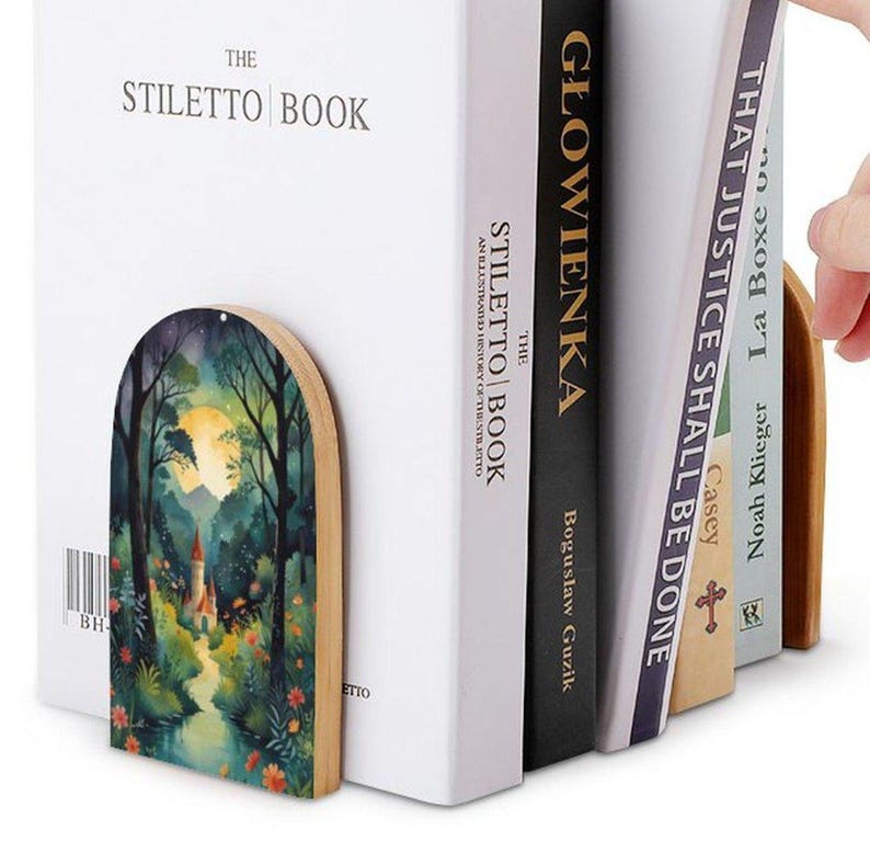 May include: Wooden bookends with a painted forest scene, holding several books. The bookends feature a curved top and a natural wood edge. The books include "THE STILETTO BOOK" and "THAT JUSTICE SHALL BE DONE".