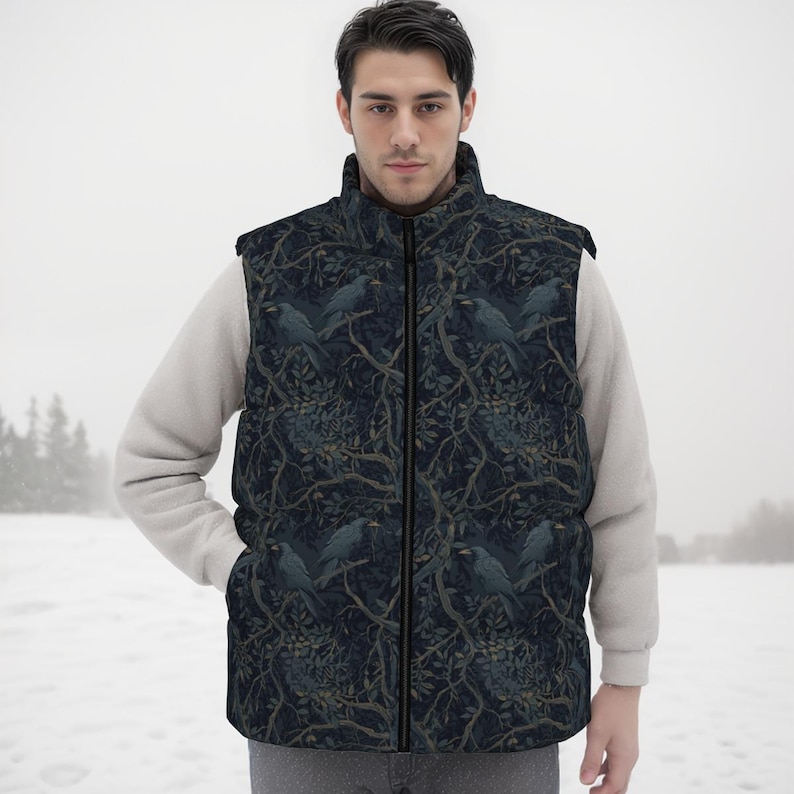 May include: A sleeveless puffer vest featuring a dark navy blue and black pattern of crows perched on tree branches. The vest has a high collar, a full-length front zipper, and is worn over a light beige long-sleeved sweater in a snowy setting.