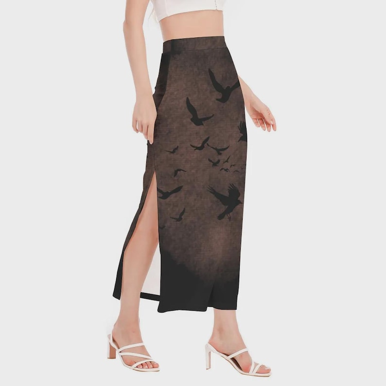 May include: A long, high-waisted skirt with a side slit. The skirt features a dark brown background with a flock of black birds in flight. The skirt is worn with a white top and white heels.