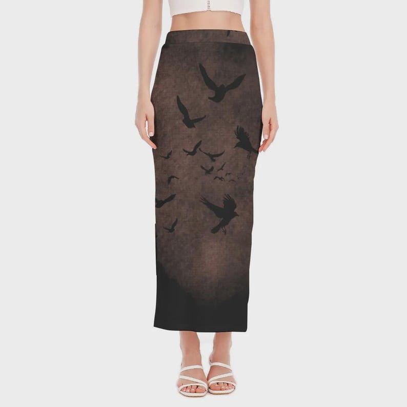 May include: A long, dark brown skirt featuring a flock of black birds in flight. The skirt has a textured, distressed appearance, with a dark gradient at the bottom. The birds are silhouetted against the brown background.