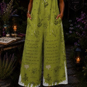 May include: A sleeveless olive green jumpsuit featuring a white drip-effect pattern at the neckline and hem. The fabric is printed with botanical illustrations and text that reads, Always honor yourself, all you give lets shoulder keep rosemary by your garden gate. Plant lavender be loyal. And live as one can wherever you can.