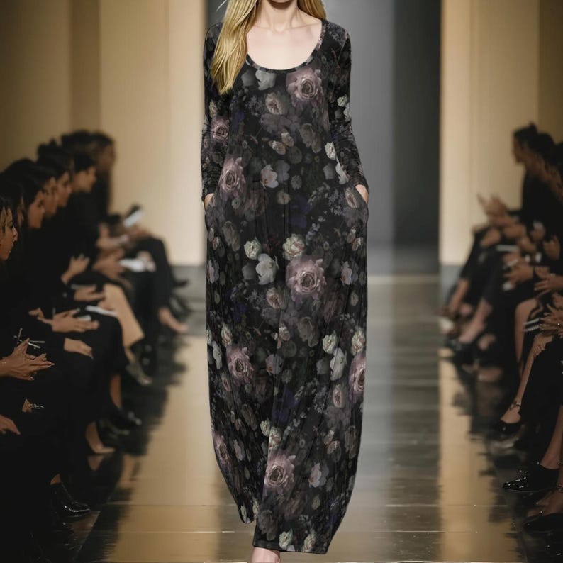 May include: A long-sleeved maxi dress featuring a dark black base with a repeating floral pattern in shades of muted purple, grey, and white. The garment has a rounded neckline and includes side pockets, falling to the floor in a straight silhouette.