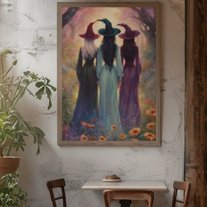 May include: A framed wall art print depicting three figures standing with their backs to the viewer in a field of flowers. Each figure wears a long dress and a pointed hat in shades of red, teal, and purple, set against a soft, glowing forest.