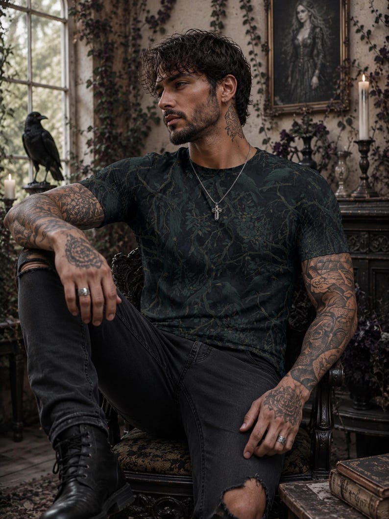 Pode incluir: Uma t-shirt de manga curta verde-escura com um padr&atilde;o subtil de floresta e p&aacute;ssaros, combinada com cal&ccedil;as de ganga pretas desgastadas e botas de couro pretas. O conjunto inclui um colar com pendente de cruz e an&eacute;is de prata nos dedos.